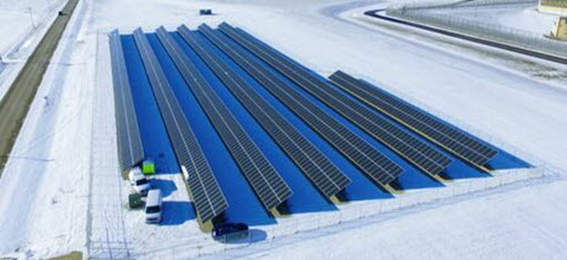 Daytime aerial view of a solar farm at Thomson Penitentiary in winter with snow on the ground